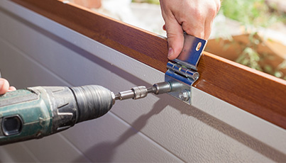 Technician repairing a garage door with a drill